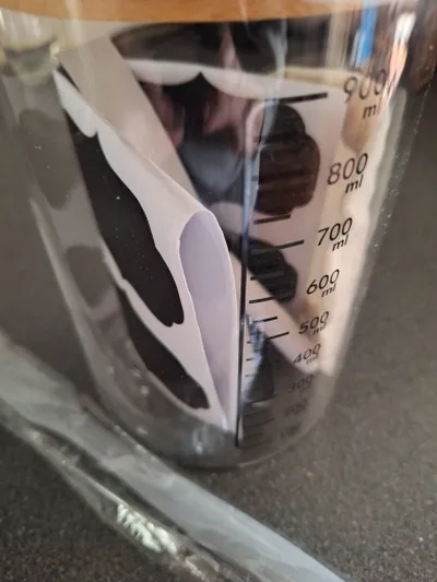 Close-up of the graduated glass jar showing the printed scale from 100 to 900 ml under the wooden lid