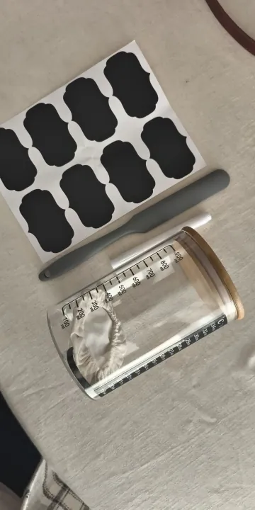 Jar lying beside the sheet of chalk labels and an elastic feeding band