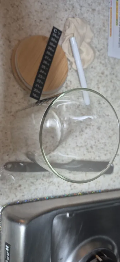 The empty jar on its side by a sink with the wooden lid, a cloth cover and the marker pen alongside