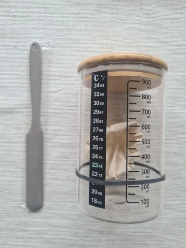 Graduated jar with wooden lid and stick-on thermometer showing the temperature scale, spatula alongside